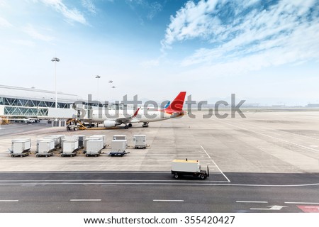 vehicles and ariplane parking in airport ramp in cloudy sky