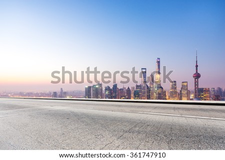 empty concrete road and cityscape in blue sky at dawn