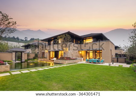 modern building by the fishpond and beautiful meadow in colorful sky at twilight