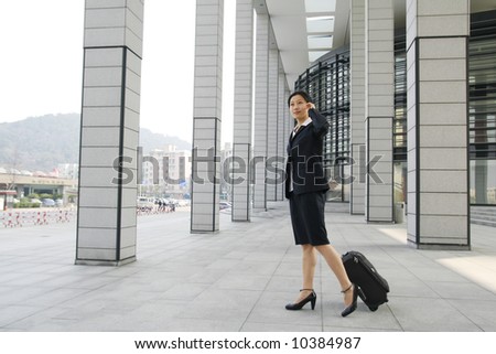 Businesswomen walking along pulling his travel luggage.
