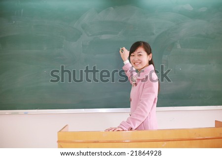 Pretty   young asian  teacher in front of a blackboard