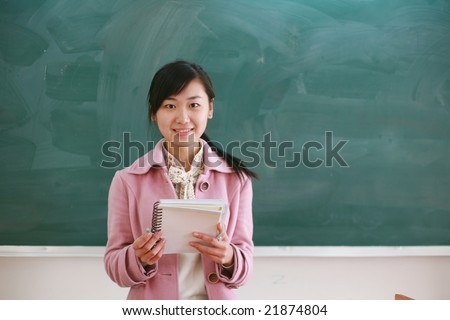 Pretty young asian teacher in front of a blackboard