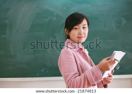 Pretty young asian teacher in front of a blackboard