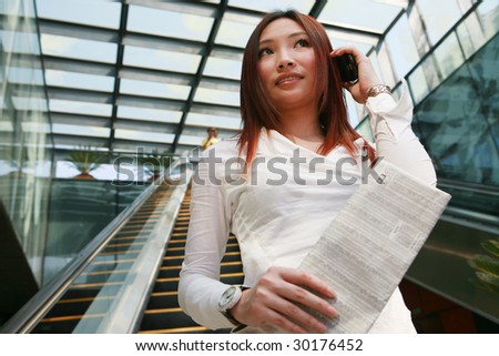 young asian business women holding mobile phone and newspaper