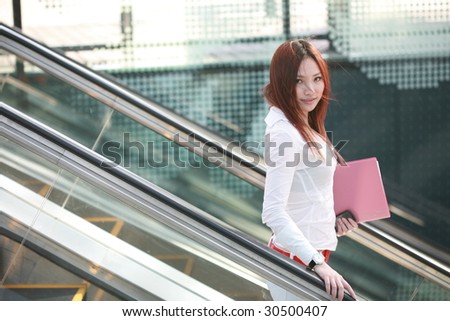 young asian businesswomen holding folder on escalator