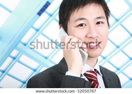 a businessman is standing  in office and answering the phone