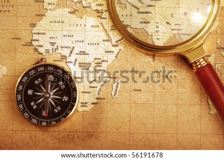 An old brass compass on a Treasure map background ,with Magnifier