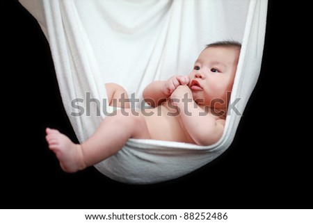 Naked Baby sleeping in White Hammock Sling, isolated on a black background.