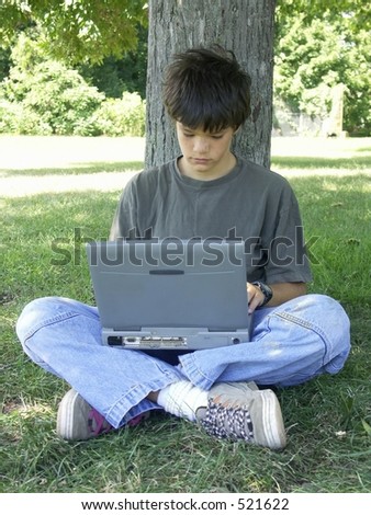 teenager and computer under a tree