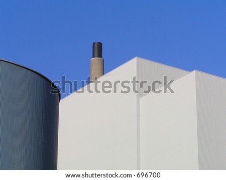 Factory buildings with smokestack against clear blue sky