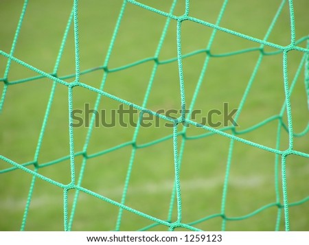 Close-up of green soccer net on blurred grass background