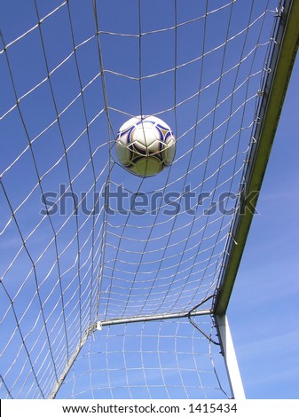 Perspective shot of soccer net with ball against clear blue sky