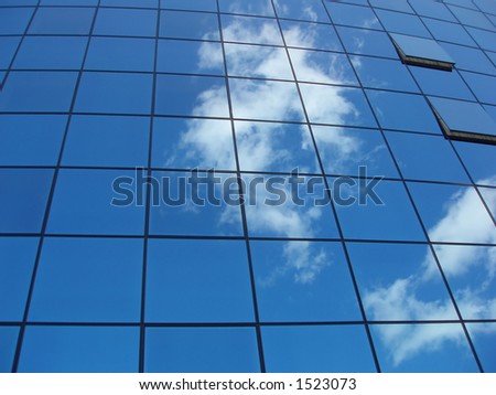 Window panels on a office building in the city with reflection of blue sky