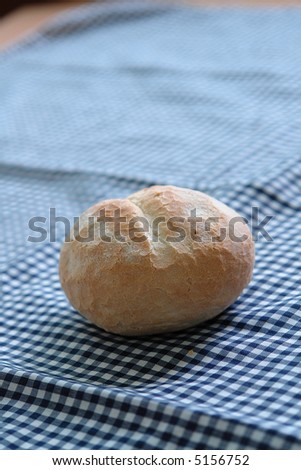 Tasty bread roll for breakfast on checkered cloth