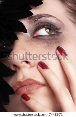 Sad young woman with smeared make-up and black feathered carnival mask