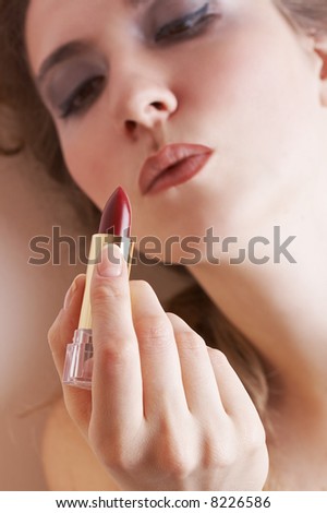 sensual blond woman about to apply lipstick, focus is on the lipstick