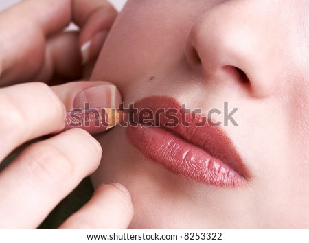 makeup artist tracing lip contour of  beautiful full lips of a girl