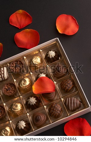 background of dark, milk, and white chocolates and orange rose petals
