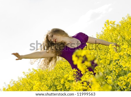 portrait of a happy girl in motion in a field with rapeseed yellow flowers, \