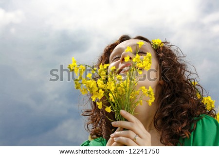 beautiful girl smelling yellow  flowers against the sky, enjoying summer time