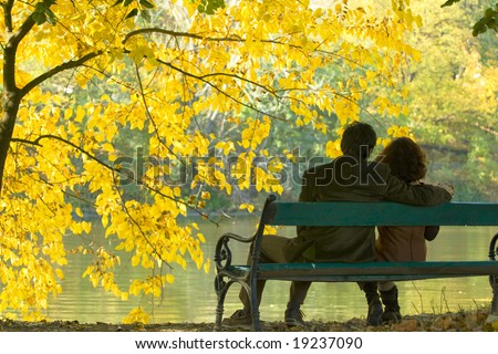 romantic couple on a bench by the lake in autumn