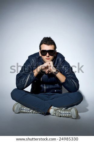 young trendy man wearing leather jacket and sunglasses