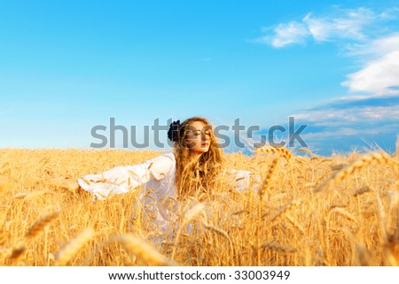 woman relaxing in wheat field at  sunset, outdoor freedom