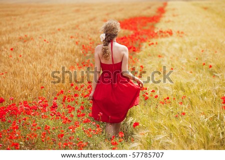 young beautiful woman walking through a  poppy field in summer