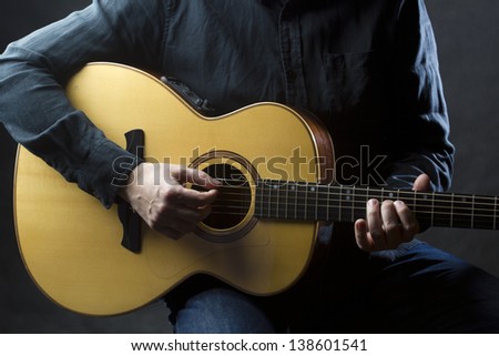 Playing acoustic guitar Detail of man playing acoustic guitar. Selective focus.