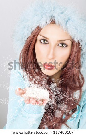 Snow queen in blue blowing the magical snow