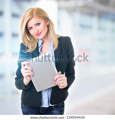 Attractive businesswoman in front of office holding digital tablet
