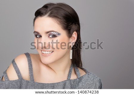 Elegant young woman wearing sparkling dress and makeup
