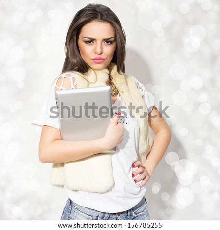 Fashionable young woman holding tablet wearing fur