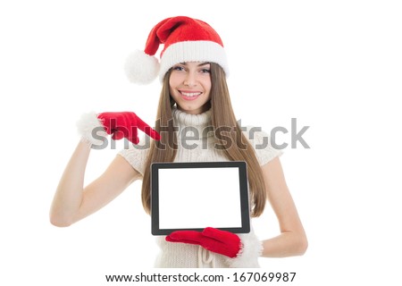 Beautiful young teenage Caucasian brunette woman with Santa beanie hat pointing at blank tablet screen showing it. Copy space available on screen and in the background. Christmas concept.