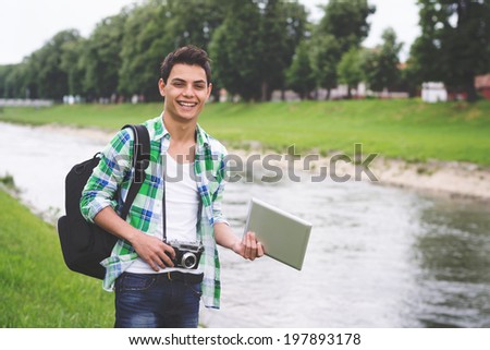 Young Hispanic hipster man tourist traveling to Europe. Mixed race hipster young man with tablet and vintage film camera.