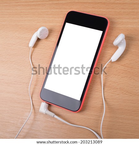 Closeup aerial view of smart phone with white isolated screen. Smart phone with earphones on wooden surface. Mock-up concept of black and red smart phone with headphones on wooden table background.