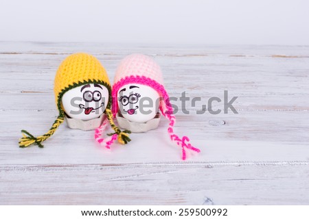 Two Easter eggs with colorful knit hats and faces. Couple of Easter eggs with hand drawn faces with colorful knit hats. Copy space, horizontal, very mild retouch.