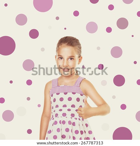 Cute little Caucasian girl in white dress with purple dots gesturing thumbs up. Square format image, retouched, filter applied, beige background with random purple dots.
