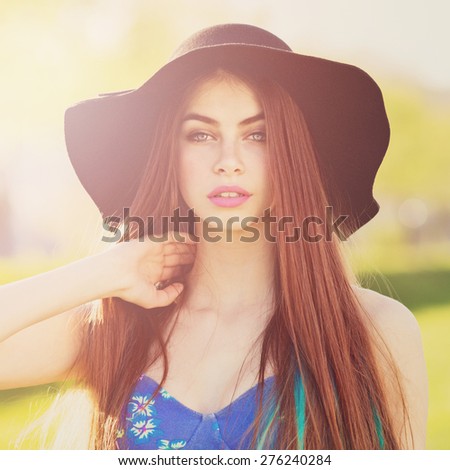 Gorgeous bohemian styled fashionable young woman in blue floral dress and fedora hat posing. Closeup portrait of trendy blue eyed redhead girl with makeup. Retouched, filter applied, square format.