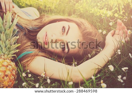 Closeup of beautiful blonde young fashion model\'s face. Gorgeous young woman lying in green grass in park on sunny summer day. Square format, retouched, vibrant colors.