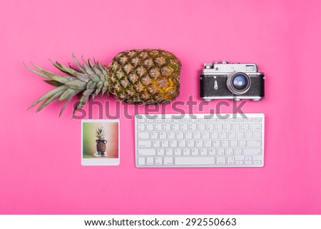 Pineapple, analog camera, photograph print and wireless keyboard on pink background. Horizontal, no retouch, vibrant colors.
