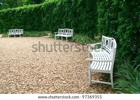 Three white chairs on the stone in the garden