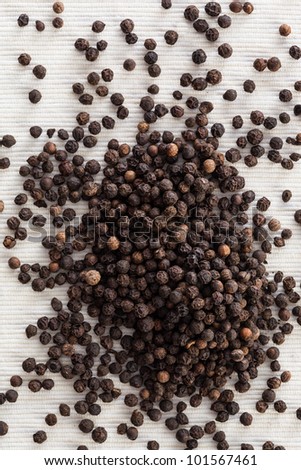 View of black pepper from the top on a white textile background.
