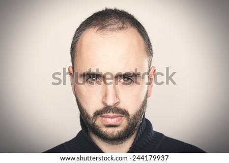Confident man looking at camera in a grey background.