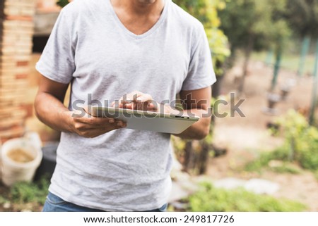 Young man using tablet in rural outdoor.