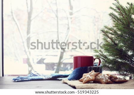 slide figure ginger cookies lying under a green tree on a background of mug and a winter window / warming atmosphere before Christmas