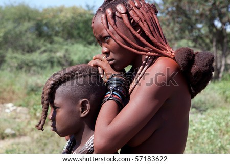 KAOKOLAND, NAMIBIA - MAY 9: An unidentified woman and child with Himba ethnic hairstyles wait for folk art products trade to begin on May 9 2010, in Himba Village near the Kamanjab, Namibia
