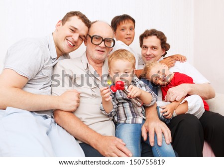 Big family. Generations. Men. Sitting on sofa smiling and looking to the camera.