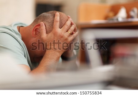 Worried Businessman Sitting In Front Of His Computer With His Head In His Hands