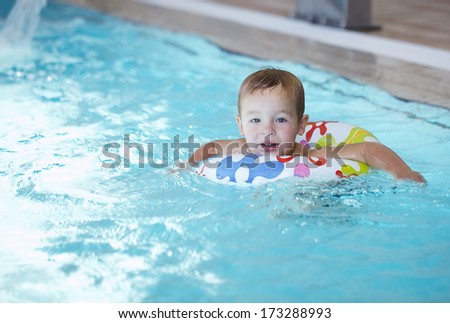 Kid learns to swim using a plastic water ring in the swimming pool or waterpark